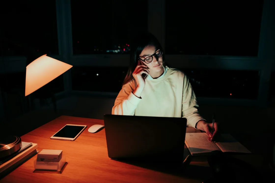 Remote worker at laptop at night, illustrating async collaboration for distributed teams comparing 2025 tools for docs, tasks, async video updates, and whiteboards.